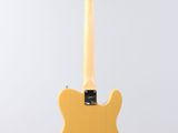 a yellow electric guitar hanging from a string on a white background
