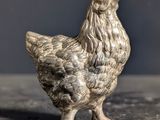 a silver chicken figurine sitting on a table