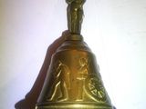 une cloche en or surmontée d'une statue