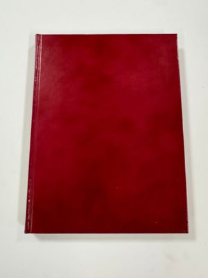 a red book sitting on top of a table next to a white wall