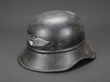 an old helmet with a winged emblem on it on a gray background