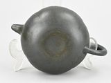 a gray vase with a black handle on a white surface