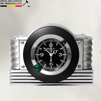 une horloge noire et argentée posée sur un socle en métal