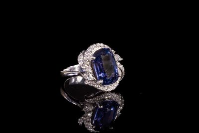 une bague ovale sertie d'un saphir bleu et de diamants, posée sur un fond noir