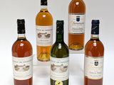 quatre bouteilles de vin posées les unes à côté des autres sur une surface blanche