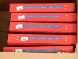 several red books are stacked in a cardboard box with labels on them