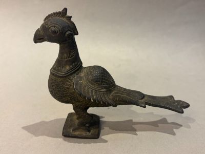 a small bronze bird that is standing on a table