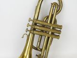 an old brass trumpet sitting on top of a white surface