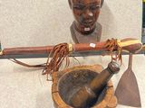 une statue en bois représentant un homme tenant un couteau et un mortier