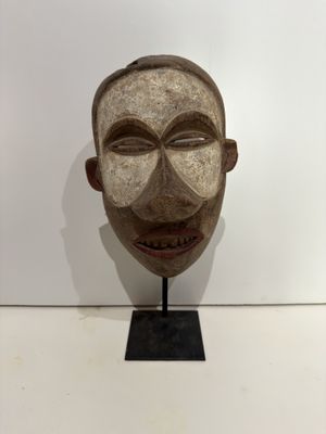 an image of a wooden mask on a stand with a white background