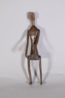 statue représentant un homme assis sur un tabouret, les jambes croisées