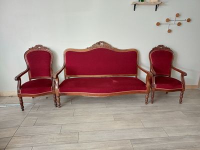 un canapé rouge et deux fauteuils dans une pièce