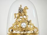 une horloge en or représentant un homme à cheval sous un dôme en verre