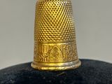a close up of a gold thimble on a black surface