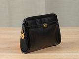 black leather purse on wooden table with grey wall in background