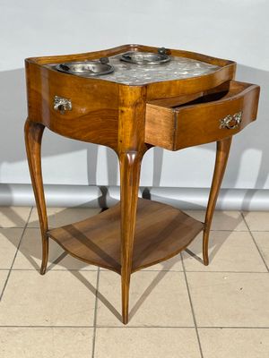 une petite table en bois avec un plateau en marbre, posée sur un sol carrelé