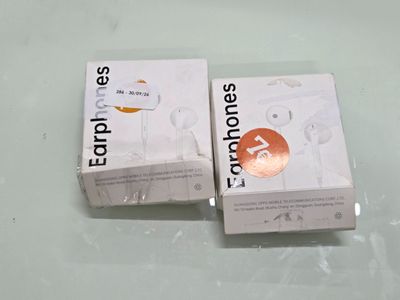two boxes of earphones sitting on top of a white table