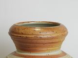 a brown and white vase sitting on a table
