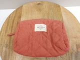 a red bag sitting on a wooden table with a label on it