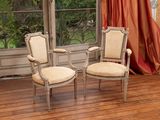 pair of antique chairs in front of a window with a red curtain