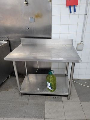 une table en acier inoxydable sur laquelle est posée une bouteille, dans une cuisine