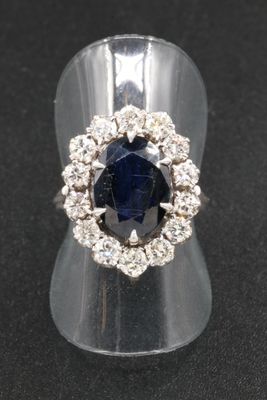 gros plan d'une bague avec une pierre bleue entourée de diamants blancs