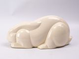 une sculpture blanche représentant un chat couché sur une surface blanche