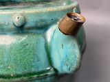 a green vase with a brass handle on a table