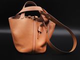 a tan leather bucket bag on a black background