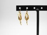 une paire de boucles d'oreilles en or posée sur un support noir
