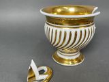 a gold and white vase with a broken handle