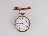 une petite montre de poche en or suspendue à une broche en or