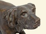 bronze statue of a dog standing on a rock on a white background