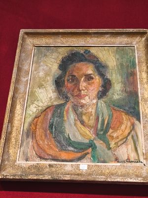 tableau représentant une femme portant un chapeau et une écharpe verts, dans un cadre doré sur fond rouge