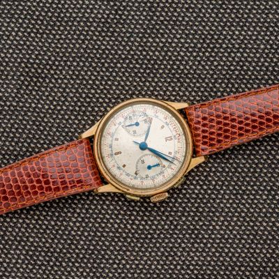 un gros plan d'une montre posée sur une surface noire, avec un bracelet marron