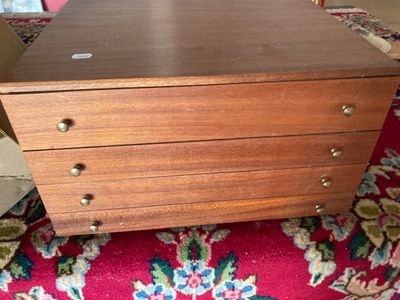 une petite commode en bois posée sur un tapis rouge