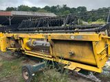 une grosse machine jaune posée au milieu d'un champ de terre battue