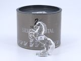 a glass horse figurine sitting in front of a tin of silver metal
