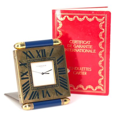 a small clock sitting next to a red book