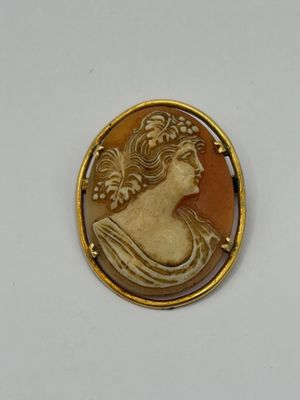 a close up of a picture of a woman ' s face on a gold plated broochle