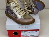 des baskets dorées et violettes à paillettes posées sur une boîte blanche