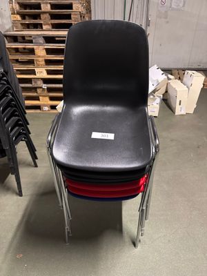 une pile de chaises dans un entrepôt, avec des palettes en arrière-plan
