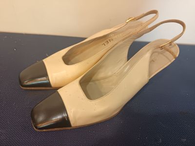 pair of beige and black shoes sitting on top of a blue surface