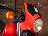 a red motorcycle parked in a garage with a brick wall in the background