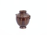 un vase brun posé sur une surface blanche