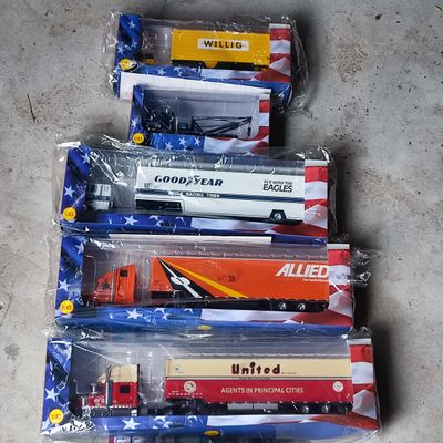 Plusieurs camions miniatures sont alignés dans des sacs en plastique posés par terre.