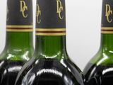 three bottles of red wine are lined up on a table