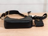 a black purse sitting on top of a wooden table next to a cell phone