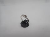 une bague en or blanc sertie de diamants, posée sur un socle noir