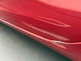 a close up of a red car that has a dent in it